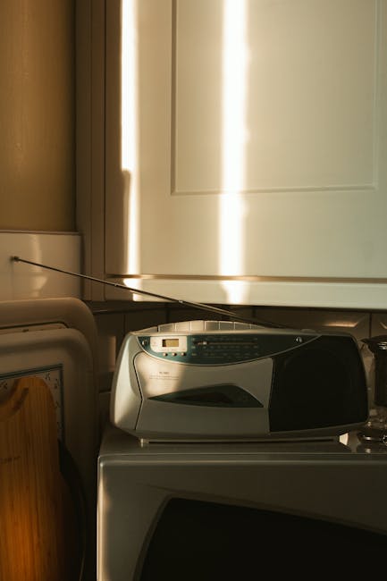 Žmogus virtuvėje klausosi radijo per telefoną ar išmanų garsiakalbį